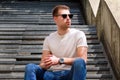 Man sitting alone on steps. Handsome boy with sunglasses. Male model posing for shooting, sitting on old stairs. Royalty Free Stock Photo