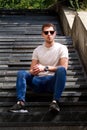 Man sitting alone on steps. Handsome boy with sunglasses. Male model posing for shooting, sitting on old stairs. Royalty Free Stock Photo