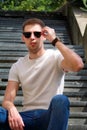 Man sitting alone on steps. Handsome boy with sunglasses. Male model posing for shooting, sitting on old stairs. Royalty Free Stock Photo