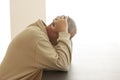 A man is sitting alone at a table head buried in his hands. A sign of grief, sadness or abandonment. - Image Royalty Free Stock Photo