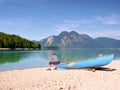 Man sitting on alpine mountain lake bank at anchored boat. Royalty Free Stock Photo