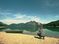 Man sitting on alpine mountain lake bank at anchored boat. Royalty Free Stock Photo