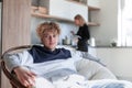 Man sitting in the armchair and young woman cooking Royalty Free Stock Photo