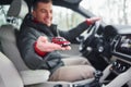 Man sitting in the automobile and holding little red toy car in hand Royalty Free Stock Photo