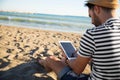 Man sitting on beach reading ebook Royalty Free Stock Photo