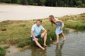 A man is sitting on the beach, a woman is walking on the water towards her friend Royalty Free Stock Photo