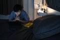 Man sitting in bedroom and using digital tablet at late night. Royalty Free Stock Photo