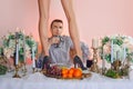 Man sitting behind the table with glass of wine and watching on female legs in high heel shoes in front of him Royalty Free Stock Photo