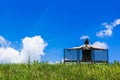 Man sitting on a bench atop grass hill