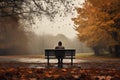 Man sitting on a bench in the autumn park and looking into the distance, rear view of a solitary person sitting on a bench in an