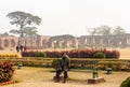 A man sitting on a bench in the gardens of the misty ruins of the ancient Adina Masjid