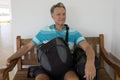 Man sitting on a bench with his suitcase and backpack Royalty Free Stock Photo