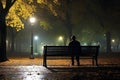 Man sitting on a bench at night in the city park in autumn