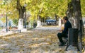 Man sitting on the bench in the park one autumn day. The alleyways of the park are covered with leaves. Romania, Baile Herculane. Royalty Free Stock Photo