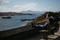 Man sitting on a bench, relaxing in the sun in Kyle of Lochalsh, Scotland.