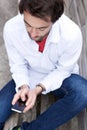 Man sitting on bench sending text message on mobile phone Royalty Free Stock Photo