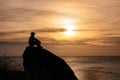 Man sitting on big rock with sightseeing of sunset in tropical sea Royalty Free Stock Photo