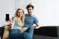 Man sitting with blonde woman holding smartphone with blank screen