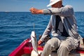 Man sitting in a boat and holding fish on hook Royalty Free Stock Photo