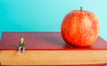 Man is sitting on a book. the concept of education. apple and books, blue background, place for text, back to school, copy space Royalty Free Stock Photo