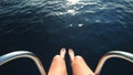 Man sitting at the bow of the boat with feet and legs overboard