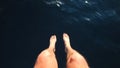 Man sitting at the bow of the boat with feet and legs overboard