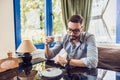 A man sitting in a cafe and looking at his watch and drink coffee