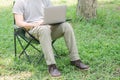 Man sitting on camping chair and working with laptop computer in the garden Royalty Free Stock Photo