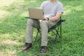 Man sitting on camping chair and working with laptop computer in the garden Royalty Free Stock Photo