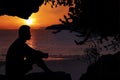 Man sitting in a cave near the beach with the sunrise Royalty Free Stock Photo