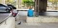 Man sitting on cement or concrete bench and waiting for someone beside bicycle and pigeon walking on the back with car movement