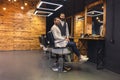 Man sitting on chair in barbershop with his master hairdresser.
