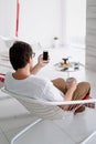Man sitting in a chair watching tv holding tea cup and phone Royalty Free Stock Photo