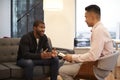 Man Sitting On Couch Meeting With Male Counsellor In Office