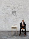 Man sitting on desk and physic formula on wall