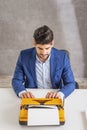 Man sitting at desk and using retro typewriter Royalty Free Stock Photo