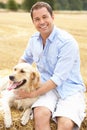 Man Sitting With Dog On Straw Bales In Harvested F Royalty Free Stock Photo