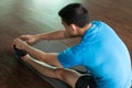 Man sitting down on exercise mat while touching his toes
