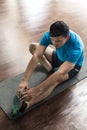 Man sitting down on exercise mat while touching his toes