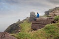 Man sitting on a edge of a cliff and looking at beautiful and rough terrain around him. Cliffs of Moher, county Clare, Ireland. Royalty Free Stock Photo