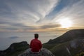 A man sitting and enjoying sunrise on the rock at the top of Gede Pangrango Mountain Royalty Free Stock Photo