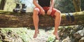 Man sitting on a fallen tree log over the mountain forest river while he waiting for socks nd trekking boots laundry drying. Royalty Free Stock Photo