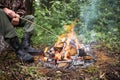 The man sitting by the fire in the forest.