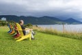 A Man Sitting in the First of a Row of Bright and Colorful Adirondack Chairs Facing the Ocean