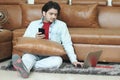 Man is sitting on the floor with holding phone in hand and using laptop Royalty Free Stock Photo