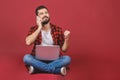 Man sitting on the floor with laptop and talking at phone. Isolated against red background Royalty Free Stock Photo