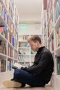 man is sitting on floor in library and reading book. education at university campus Royalty Free Stock Photo