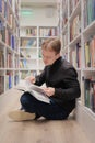 man is sitting on floor in library and reading book. education at university campus Royalty Free Stock Photo