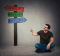 Man sitting on the floor pointing forefinger at signpost arrows shows past, present and future Royalty Free Stock Photo