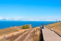 Man sitting on the floor watching on the bright blue lake Baikal. Hiking or travel concept. Exploring the great outdoors